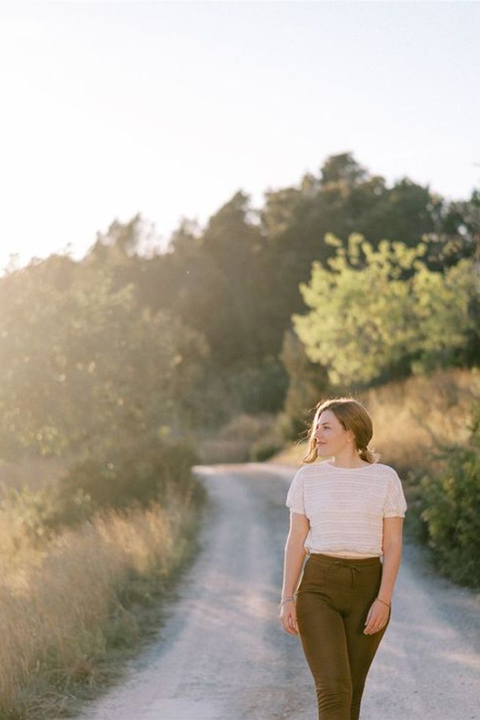 Vee walking alone down a sunlit countryside path at golden hour
